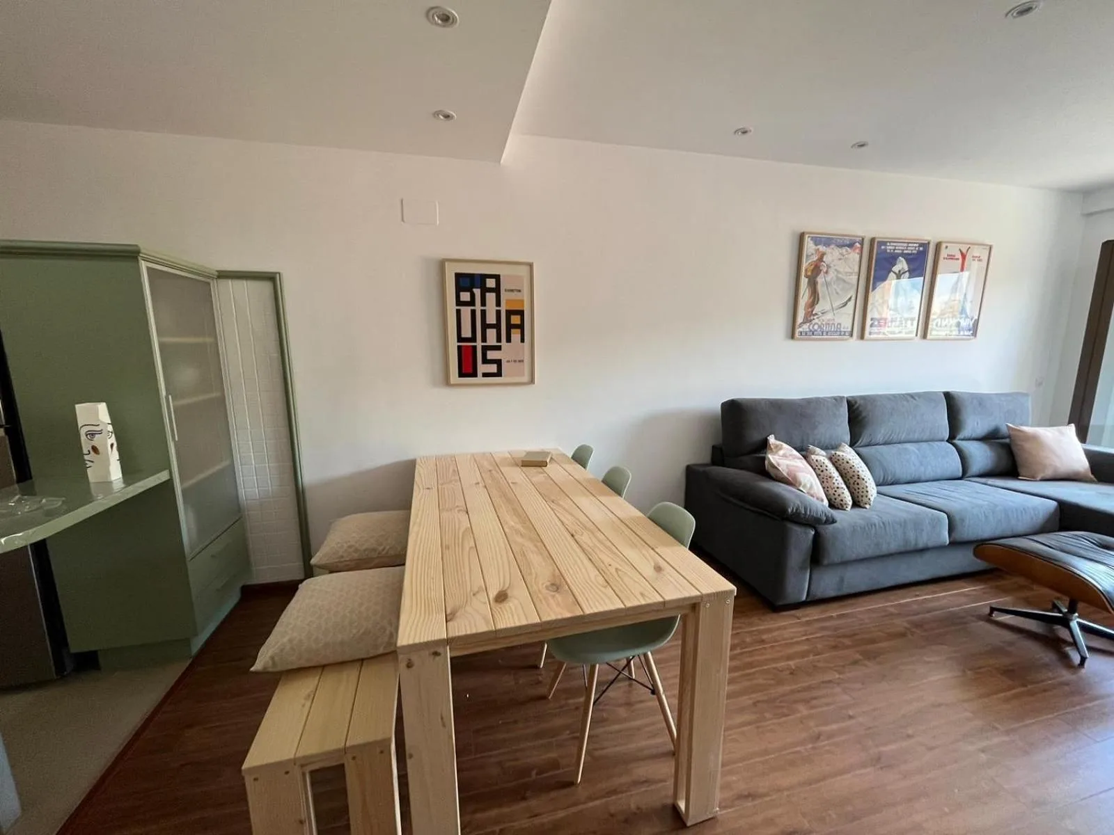 Salón abierto a la cocina y al comedor, con carteles de estaciones de esquí en la pared